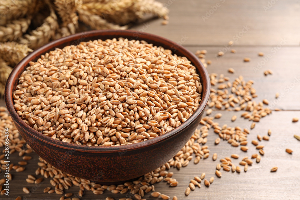 Wheat grains in bowl on wooden table, closeup Wheat grains in bowl on wooden table, closeup