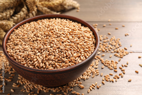 Wheat grains in bowl on wooden table, closeup