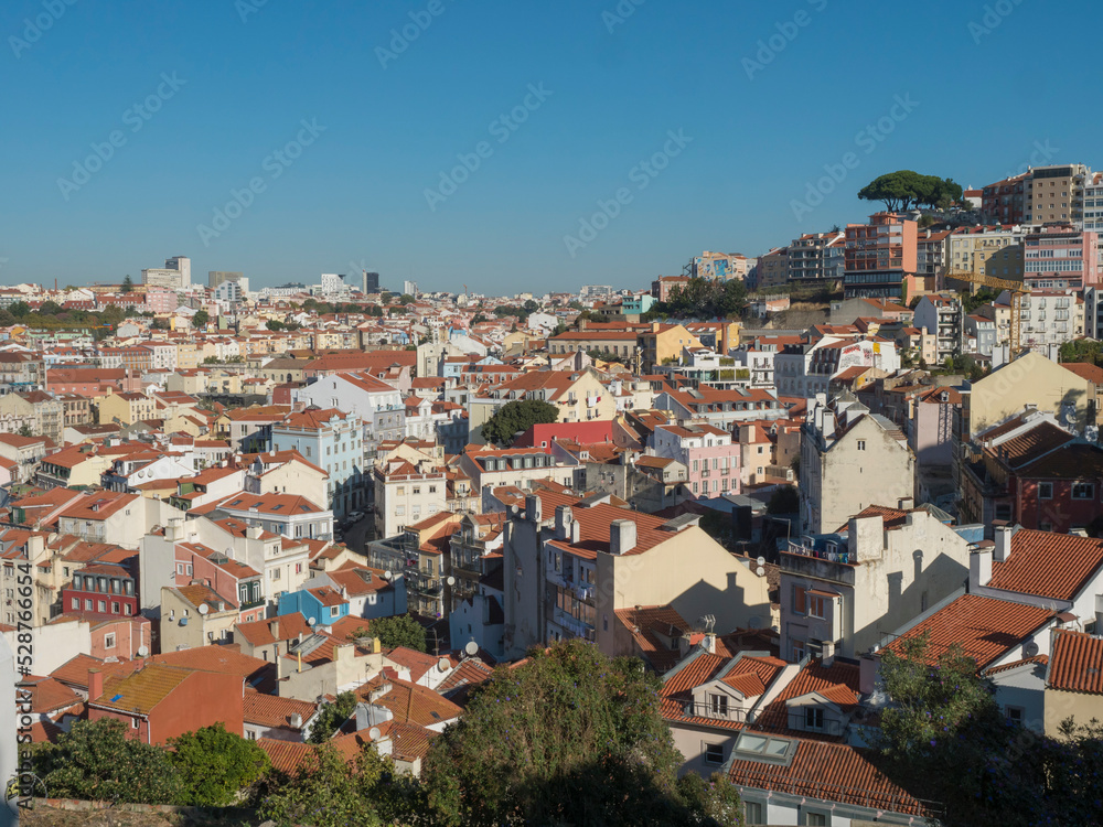 The beautiful skyline of Lisbon, Portugal, with red roofed, colorful houses in the Alfama district during a sunny day.