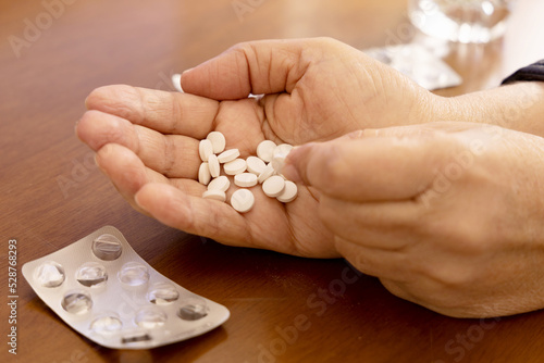 Hand holding medicine pills on wooden surface. Selective focus.