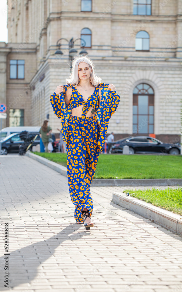 Young beautiful blonde woman in a stylish spotted summer suit walks around the city Young beautiful blonde woman in a stylish spotted summer suit walks around the city