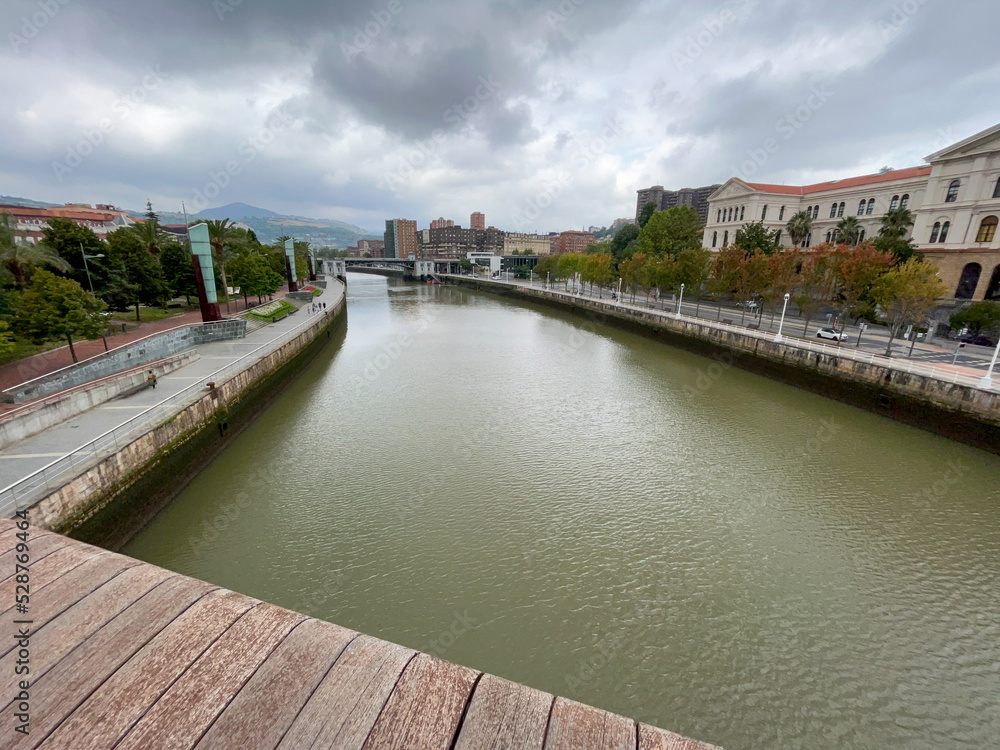 view of the immense river of bilbao from the wooden bridge on a cloudy day