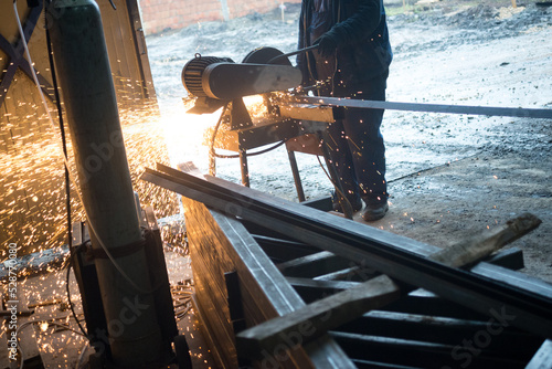 Construction worker cutting steel rods in construction factory using grinder.