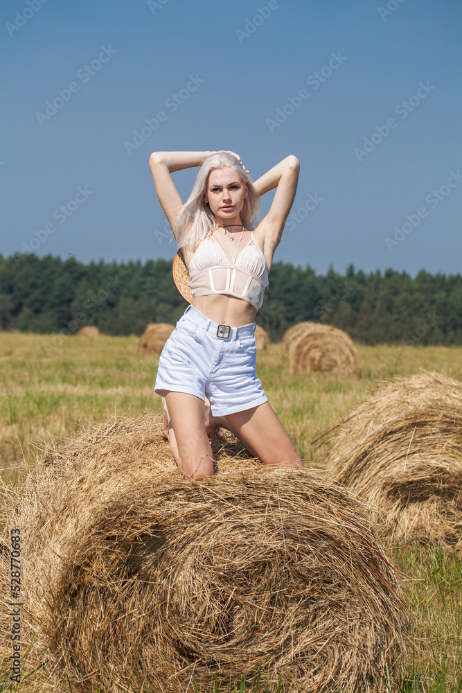 Young beautiful blonde girl in a straw hat posing in the hayloft Young beautiful blonde girl in a straw hat posing in the hayloft