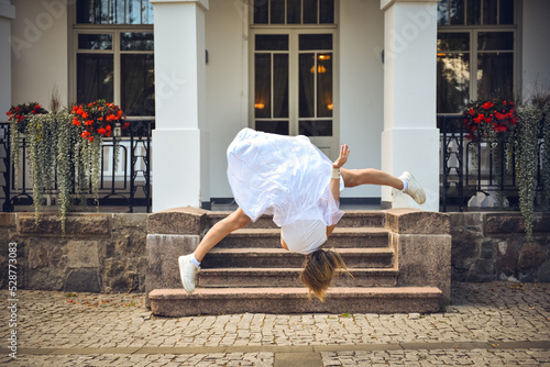 Girl athlete in a white dress makes a jump in the air