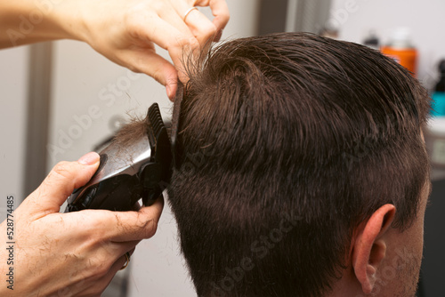 Hair salon master trimmed client hair with electric razor at barber shop. Male client getting haircut by hairdresser. Hair care, beauty industry, barber concept