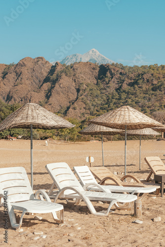 Sunbeds and rattan parasols on sandy seaside