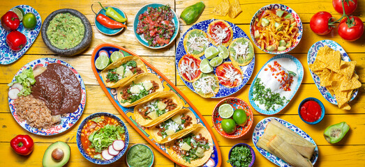 Mexican festive food for independence day independencia - chiles en nogada, tacos al pastor, chalupas pozole, tamales, chicken with mole poblano sauce. Yellow background.
