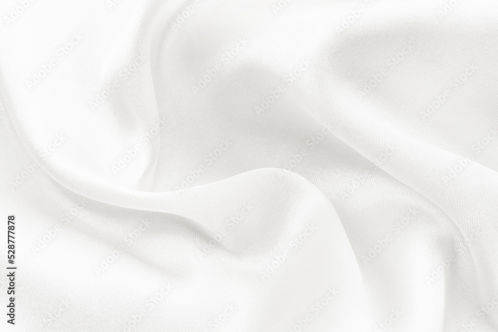 The texture of a white fabric made of silk with folds and wrinkled. Background of light material