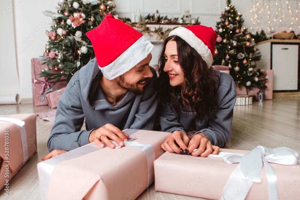 Lovely young romantic couple wear red hats sitting open gifts presents garlands home cosy interior atmosphere New Year Christmas tree decorations holiday party celebrating concept winter evening
Lovely young romantic couple wear red hats sitting open gifts presents garlands home cosy interior atmosphere New Year Christmas tree decorations holiday party celebrating concept winter evening