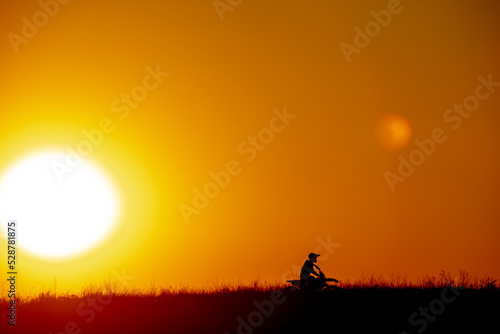 Fototapeta Naklejka Na Ścianę i Meble -  motocross at sunset silhouette of a motorcycle on the field