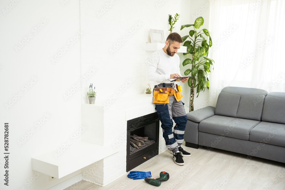 Fototapeta premium Professional technician with screwdriver installing electric fireplace in room