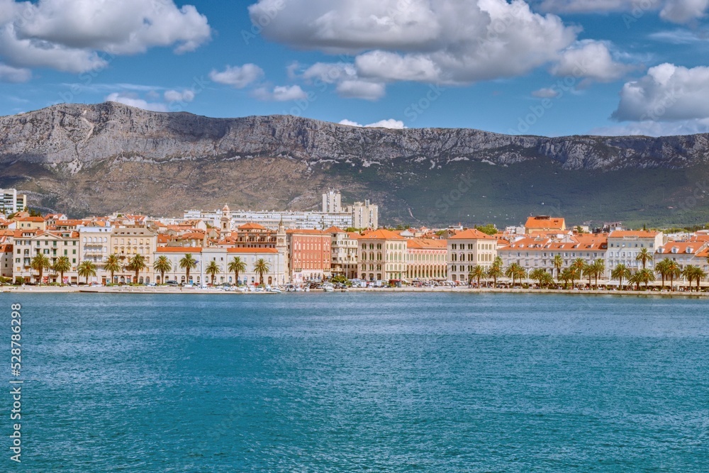 View of the harbor and old quarter of Split with the historic center and mountains in the background from the deck of a ship during a sunny and cloudy morning