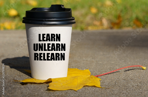 On a yellow maple leaf there is a cup of coffee on which is written - learn unlearn relearn photo