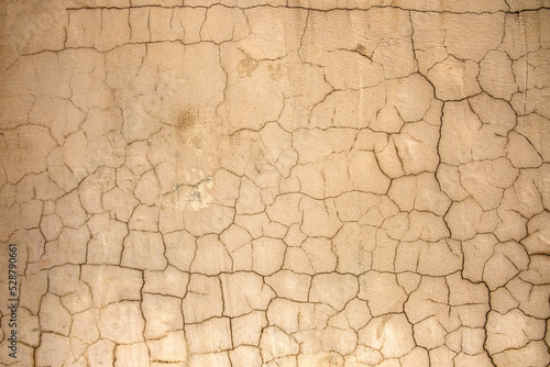 old beige wall with dark cracks. rough surface texture