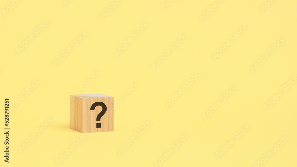 question mark drawn on wooden block over yellow background with copy space. question mark drawn on wooden block over yellow background with copy space.