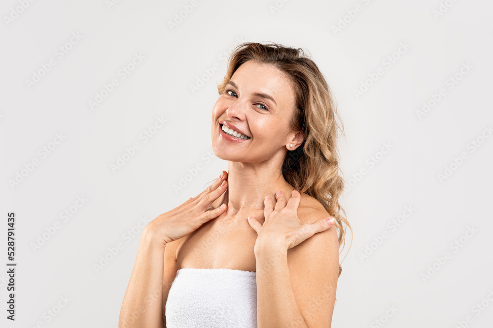 Attractive Middle Aged Female Wrapped In Towel Posing On Light Studio Background Attractive Middle Aged Female Wrapped In Towel Posing On Light Studio Background
