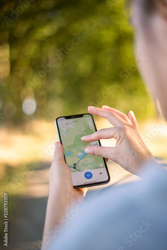 girl cyclist looks at a map on her phone and plots a route for a trip for a GPS navigator