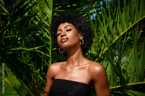 African american model tropical fashion portrait  . Beautiful woman posing  against green exotixc palms trees.