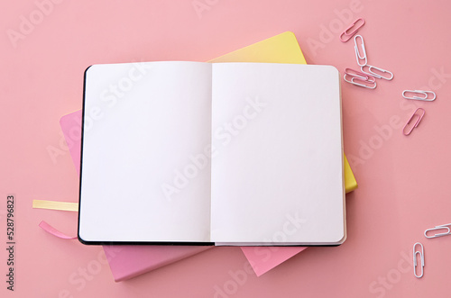 Back to school supplies stationery on pink background, flat lay, top view. Education accessories and open empty blank mockup notebook stuff. Flatlay from above. Copy space.