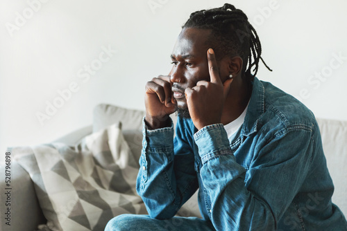 Thoughtful African American Man Thinking Touching Temples Sitting At Home