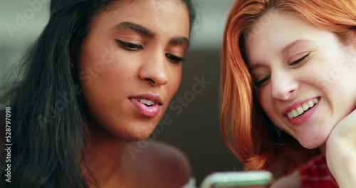 Two pretty multi-racial girls looking at cellphone screen  real laugh and smile