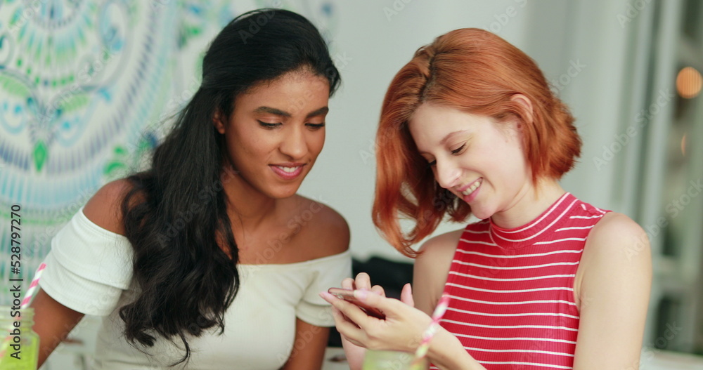 Two multiracial girls looking at cellphone screen laughing and smiling Two multiracial girls looking at cellphone screen laughing and smiling