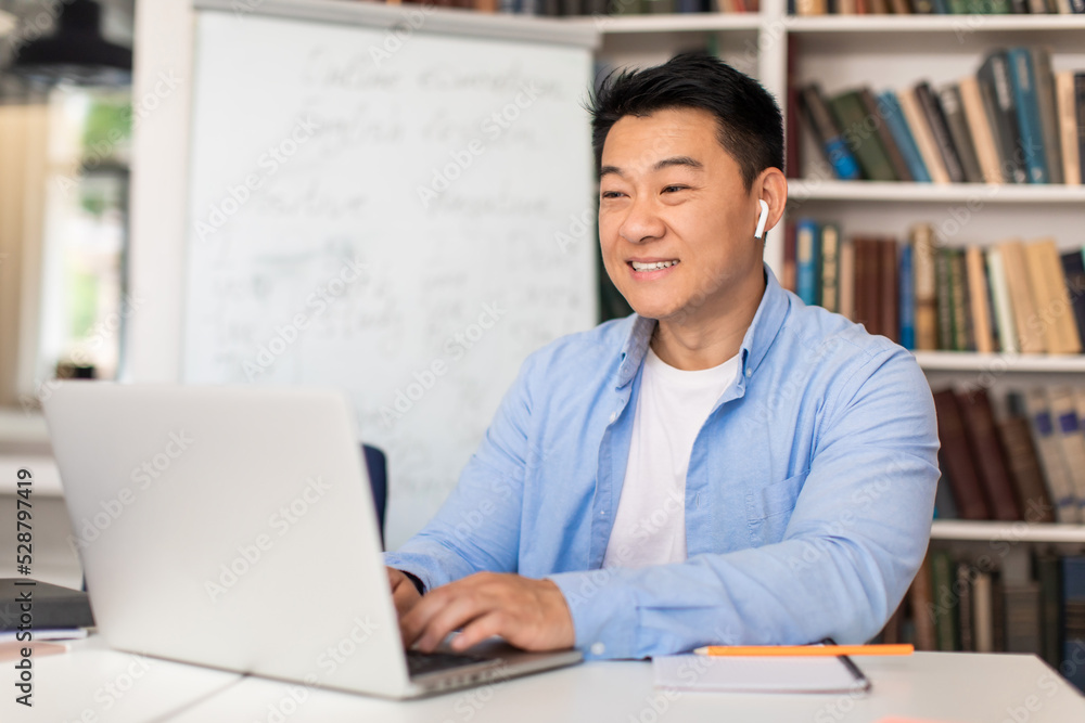 Korean Teacher Man Typing On Laptop Preparing Online Lecture Indoors Korean Teacher Man Typing On Laptop Preparing Online Lecture Indoors