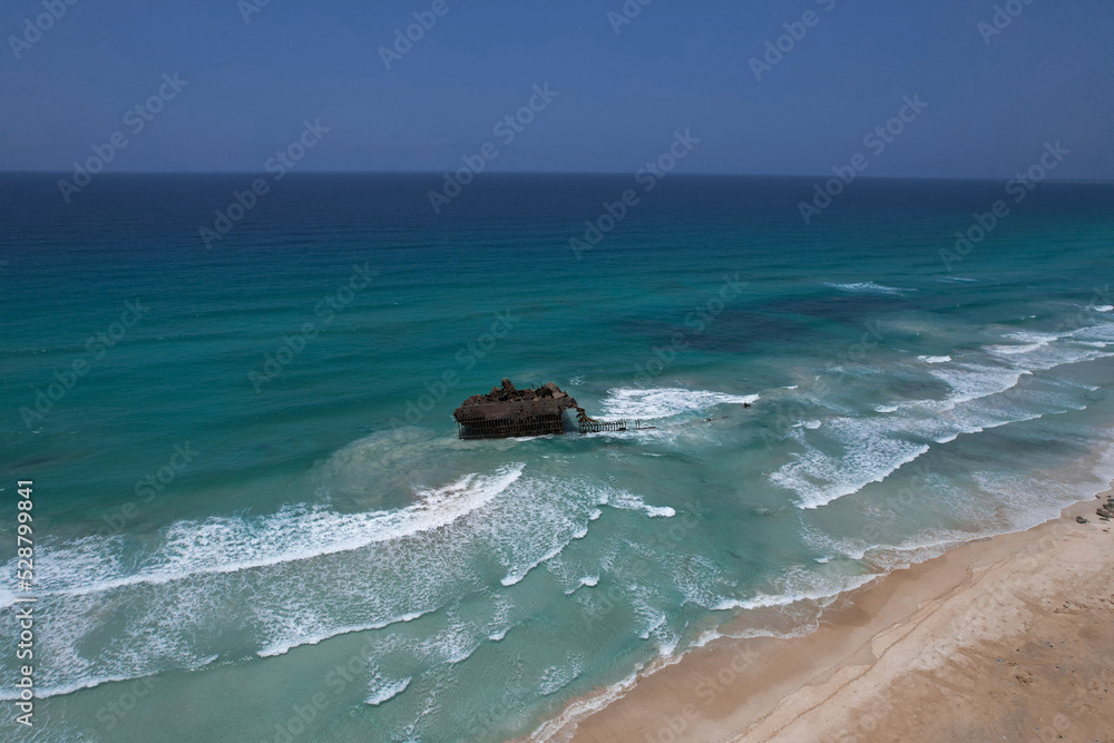 Fototapeta premium Sunken ship in the ocean near the sandy beach, drone view