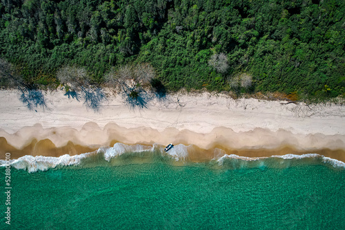 Deserted beach with waves and lonely boat, drone view