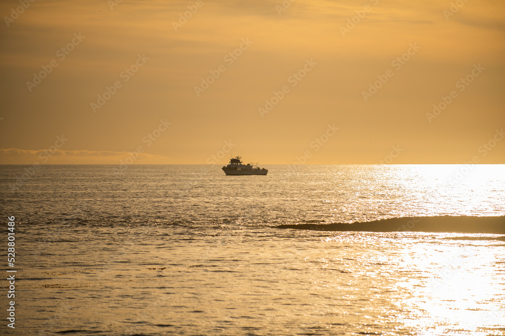 Landscape of sea and tropical beach at sunset or sunrise time for leisure travel and vacation. Reflection of sun in the water and sand on beach.