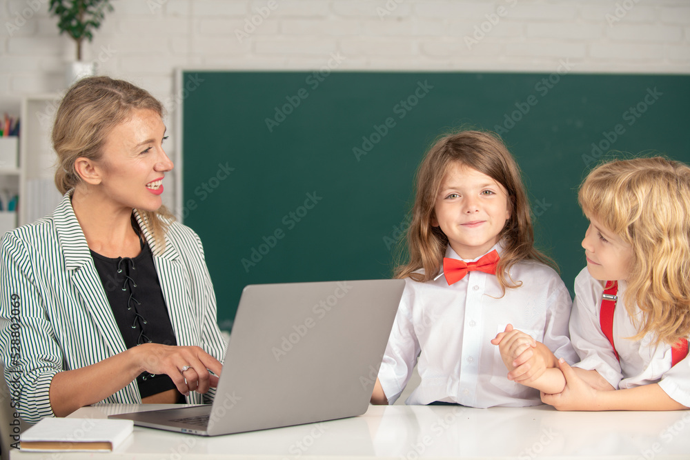 Back to school. School pupil with teacher learning at laptop computer, studying with online education e-learning in classroom. School education and children concept. Back to school. School pupil with teacher learning at laptop computer, studying with online education e-learning in classroom. School education and children concept.