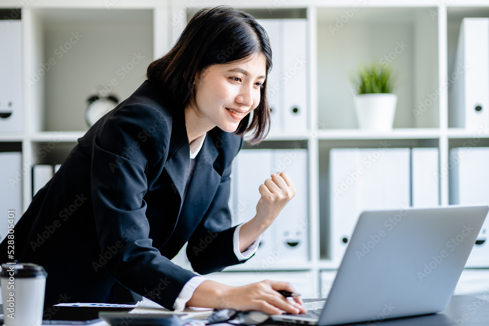 Asian businesswoman looking at laptop computer with excited and raised hands up celebrate winner success victory business , receiving reward career and good news Asian businesswoman looking at laptop computer with excited and raised hands up celebrate winner success victory business , receiving reward career and good news