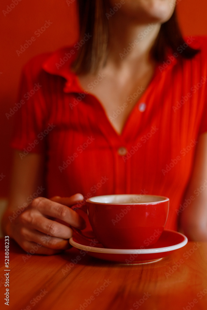 soft selective focus. woman in a red dress or polo T-shirt drinks coffee and tea from a red cup in a coffee shop or at home. a beautiful successful woman at lunch. coffee consumption and nutrition soft selective focus. woman in a red dress or polo T-shirt drinks coffee and tea from a red cup in a coffee shop or at home. a beautiful successful woman at lunch. coffee consumption and nutrition