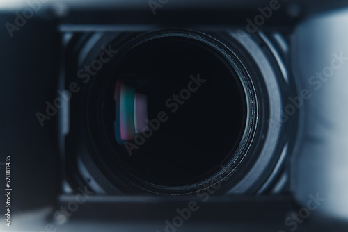 Close-up black professional camera lens with hood and color reflections. High quality photo