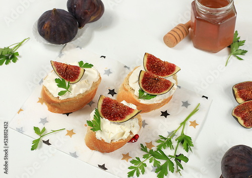 Healthy breakfast with ingredients, toast with figs and soft cream cheese and honey, Canape or crostini with fried baguette and herbs on a light sunny table, italian recipes menu, selective focus