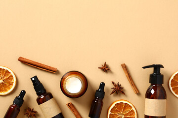Autumn fall cosmetics with cinnamon sticks, anise stars, sliced dried orange on beige background. Natural organic beauty products design. Flat lay, top view.