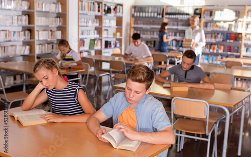 Upset efficient serious boy and girl reading books during lesson in classroom