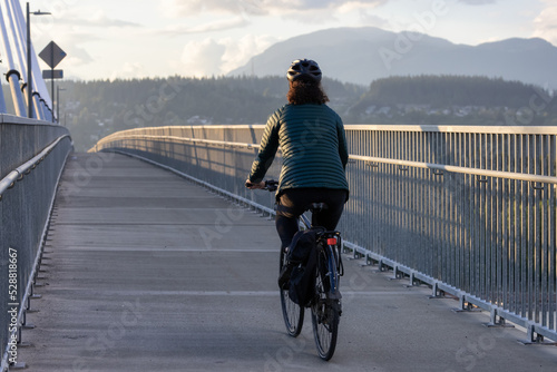 Caucasian Woman riding on a bicycle on a bike lane at Port Mann Bridge. Greater Vancouver  British Columbia  Canada.