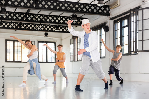 Group of teenagers training at dance class, practicing contemporary dance moves