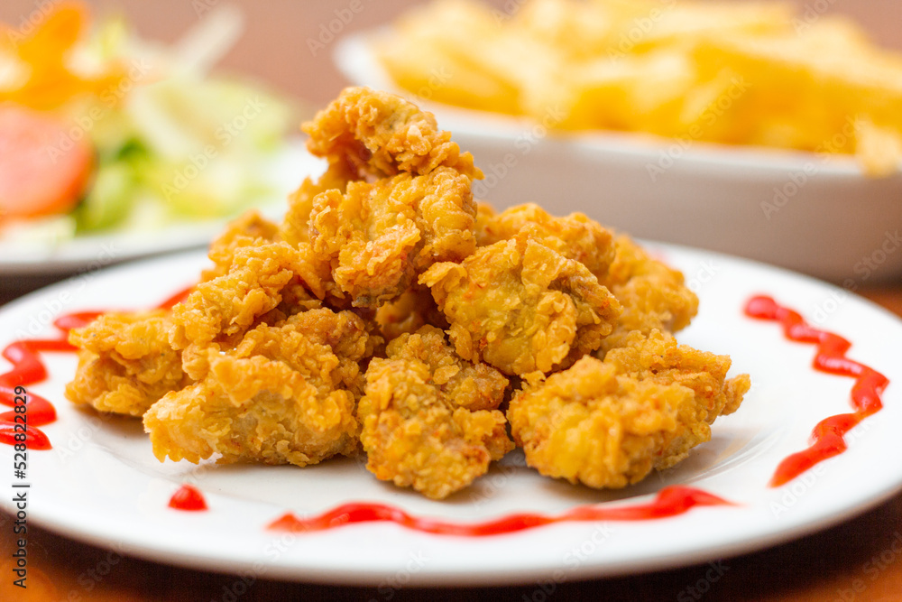 Chicken chicharron, accompanied by French fries and salad on a wooden table. Chicken chicharron, accompanied by French fries and salad on a wooden table.