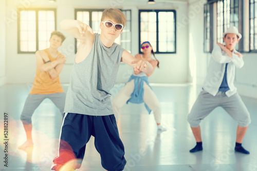 Teenage boy practicing hip hop moves with friends at group dance class