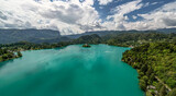 Wideangle aerial view of lake Bled island (Slovenia) with emerald green water and dramatic clouds in blurry background