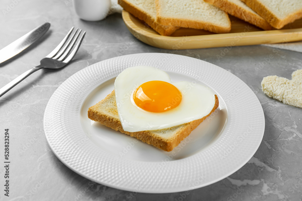 Heart shaped fried egg served on grey marble table Heart shaped fried egg served on grey marble table