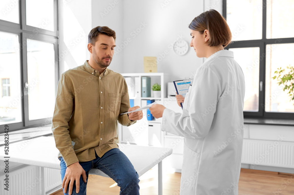Obraz premium medicine, healthcare and people concept - female doctor giving prescription to man patient at hospital