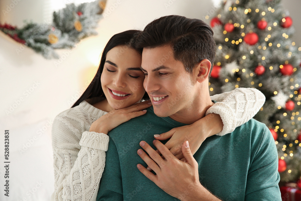 Fototapeta premium Happy couple near decorated Christmas tree indoors