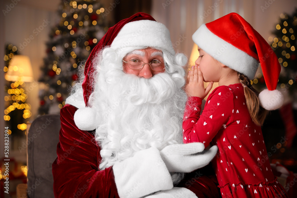 Little girl whispering in Santa Claus' ear near Christmas tree indoors Little girl whispering in Santa Claus' ear near Christmas tree indoors