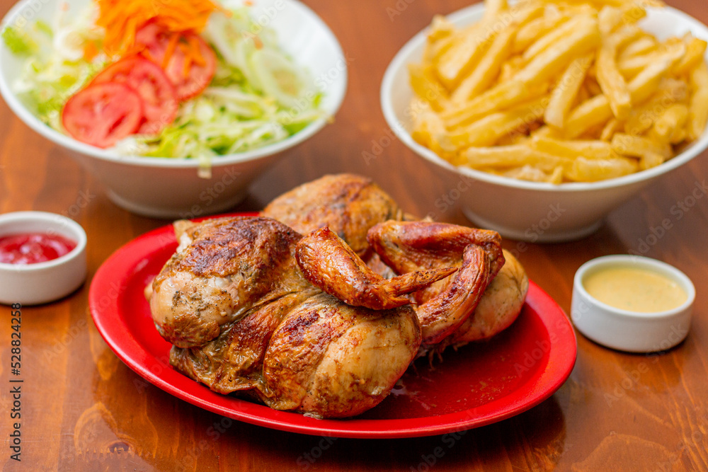 Grilled chicken with french fries on a wooden table.
Grilled chicken with french fries on a wooden table.