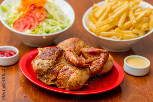 Grilled chicken with french fries on a wooden table. 