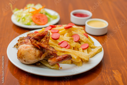 Peruvian dish called "salchipollo", grilled chicken, french fries and hotdog accompanied by salad with creams.